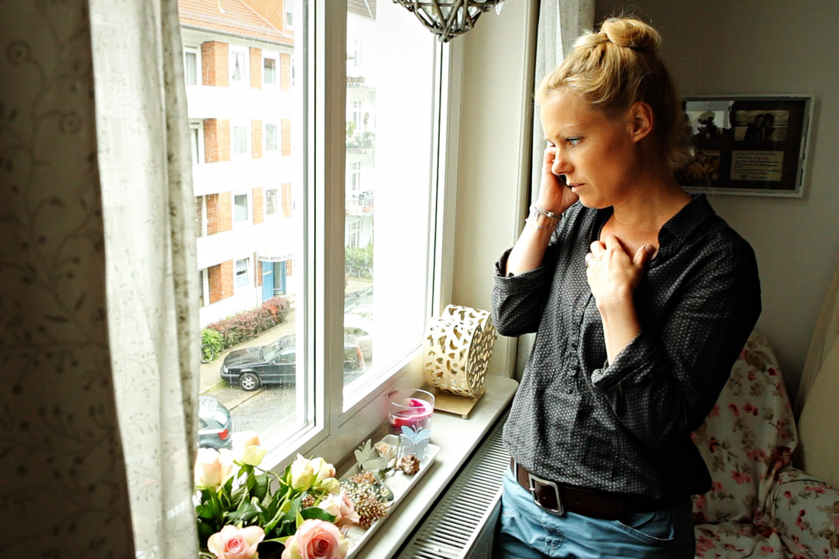 Frau schaut aus dem Fenster, während sie telefoniert