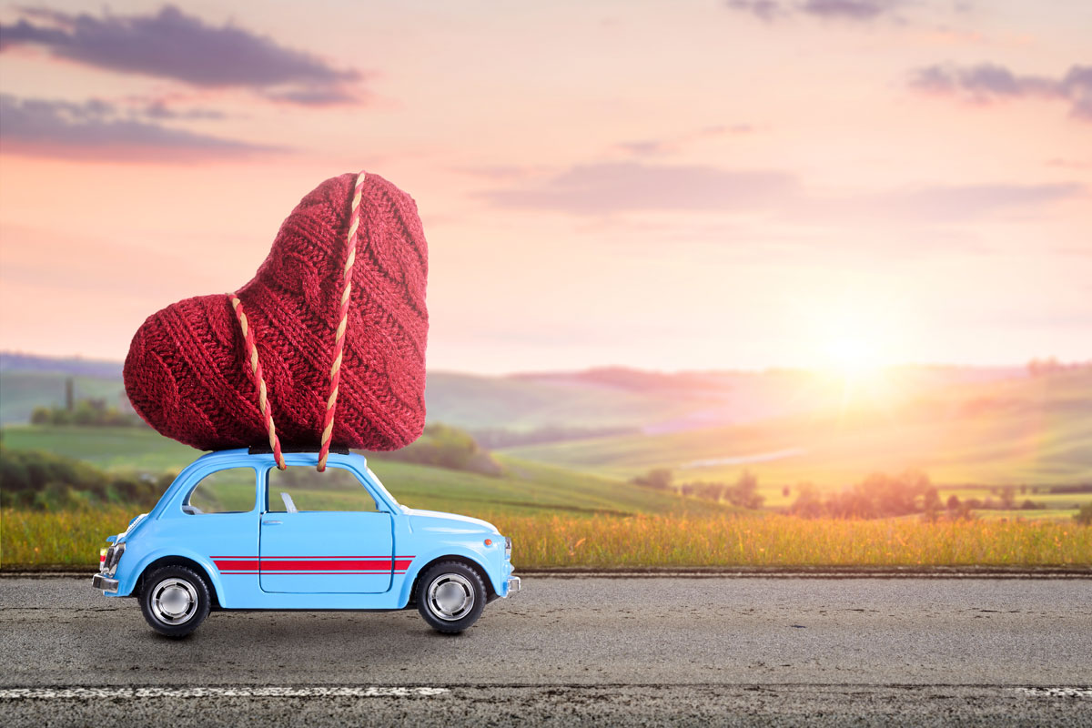 Ein Auto mit einem Herz auf dem Dach fährt auf der Straße